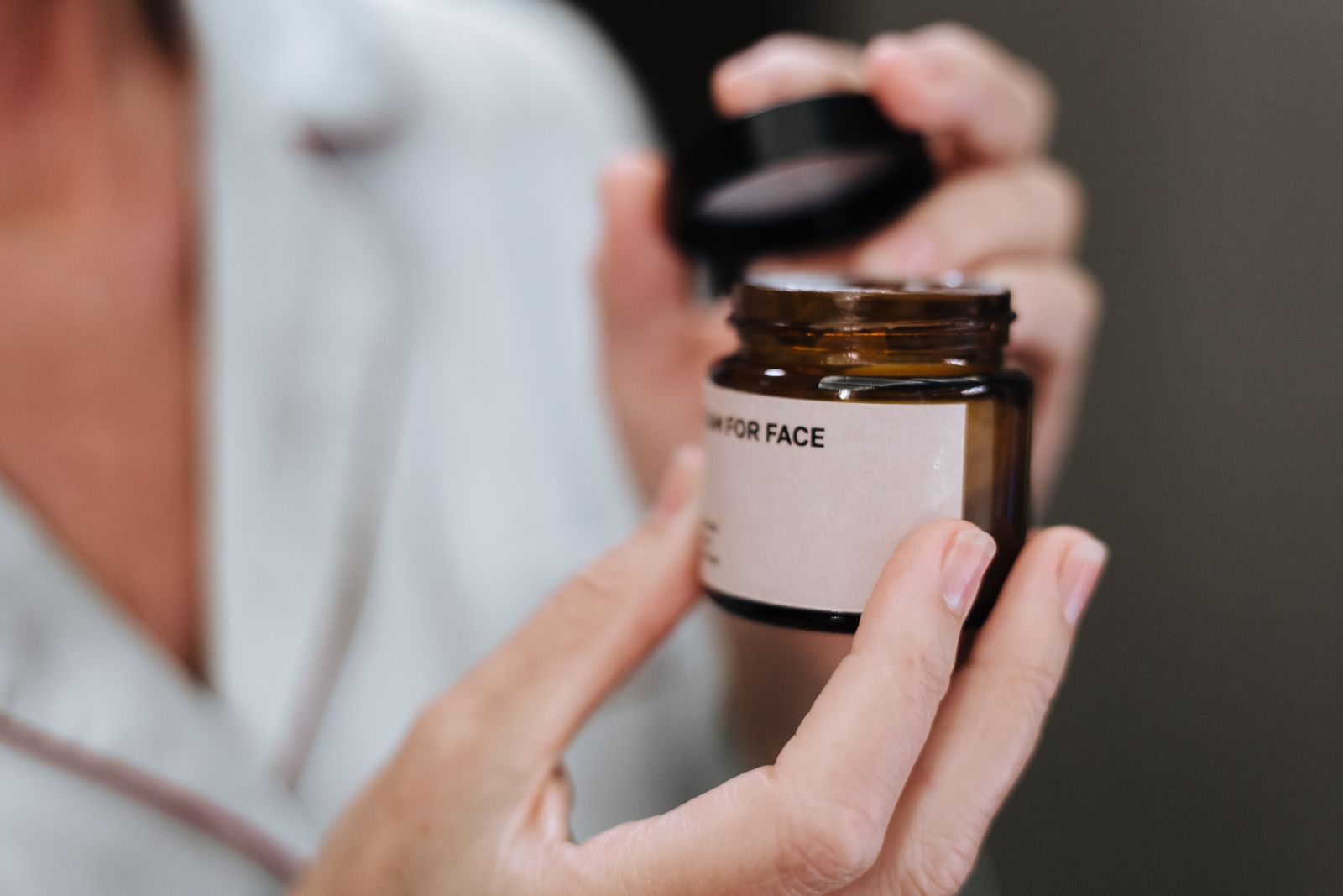 Hands opening a face cream jar