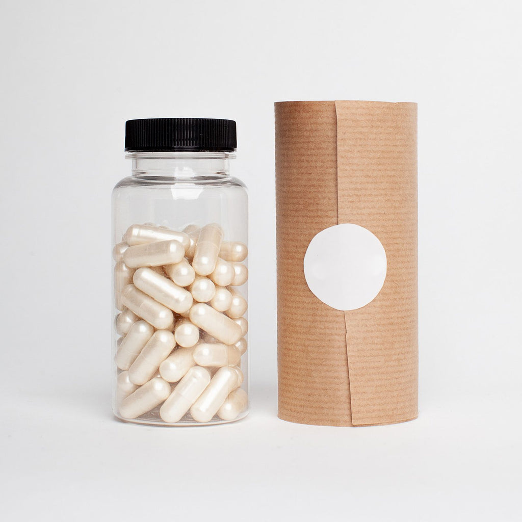 Clear bottle of white capsules with kraft packaging