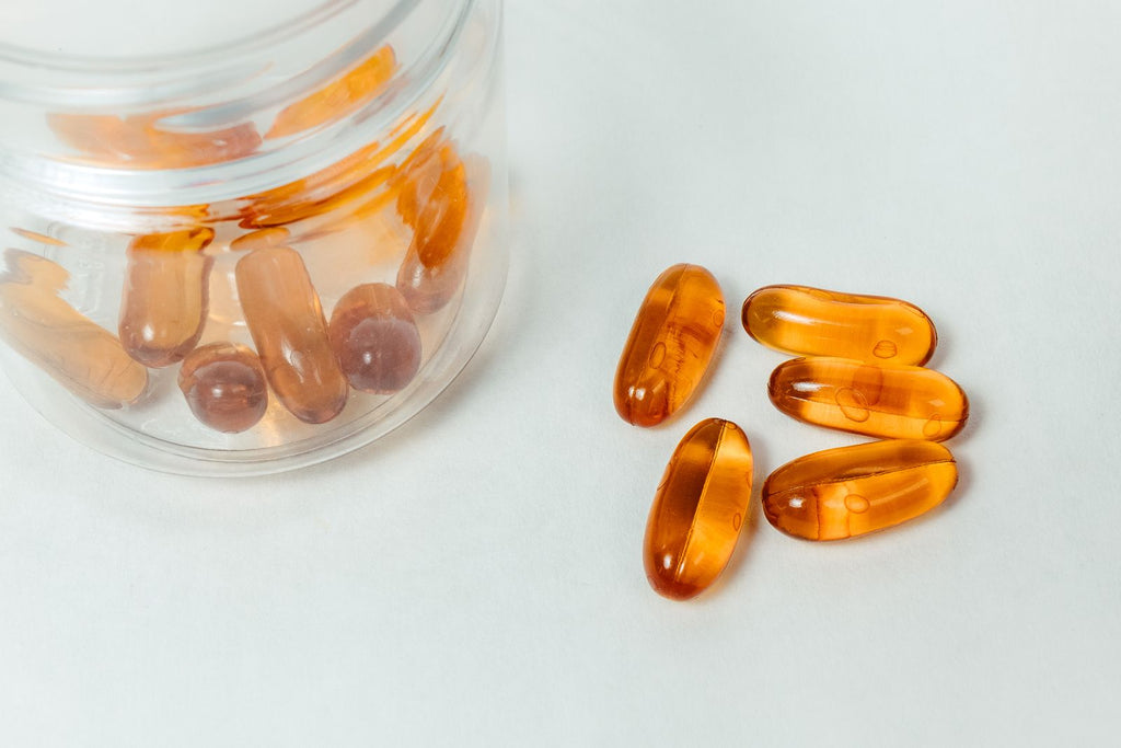 Amber softgel capsules spilling from a glass container