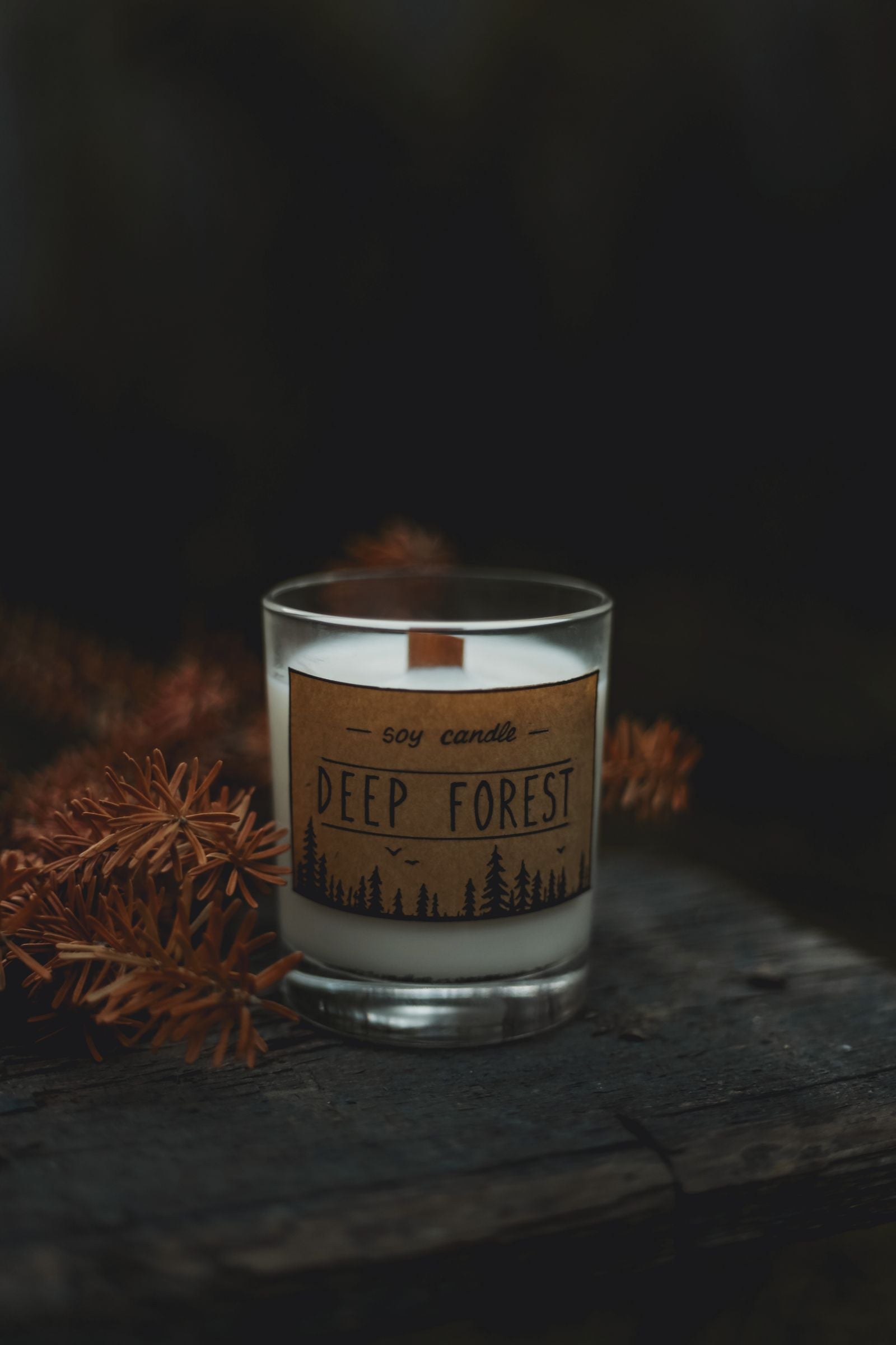 Rustic soy candle with pine twigs on wood