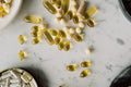 Yellow vitamin D softgels and white capsules on marble surface