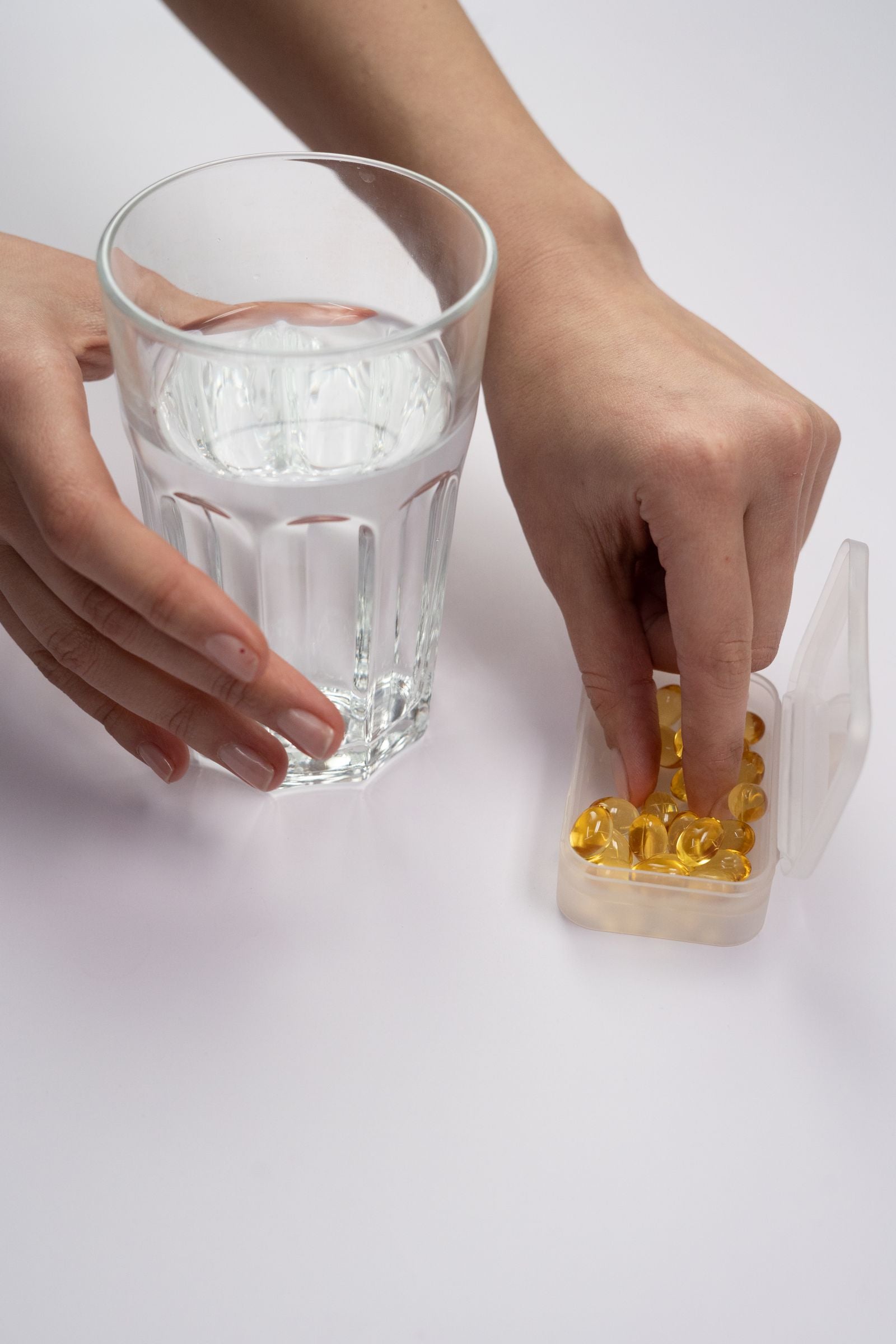 Hand taking a supplement with a glass of water