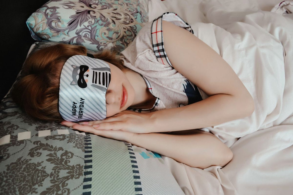 Woman wearing a sleep mask resting in bed