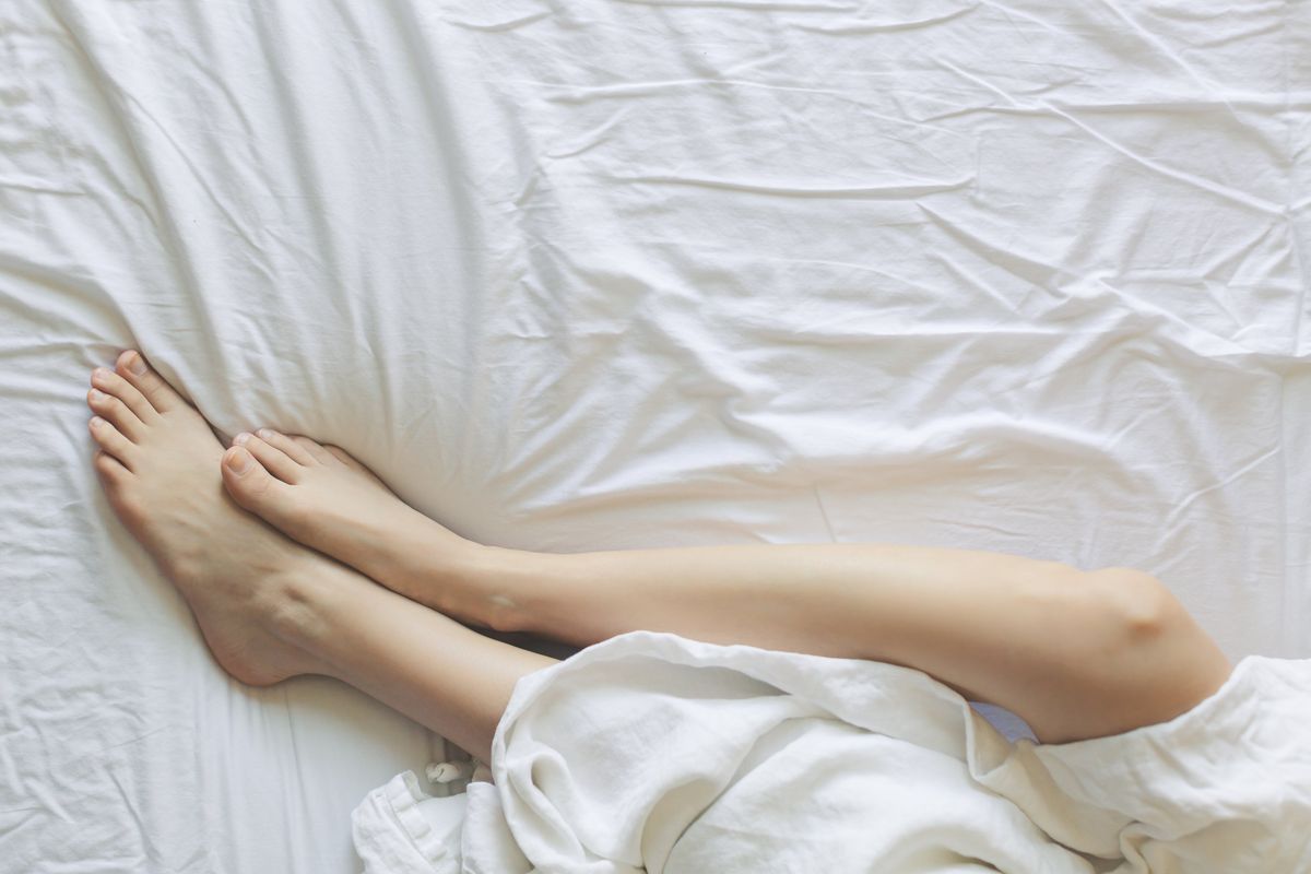 Person resting in bed under a soft weighted blanket