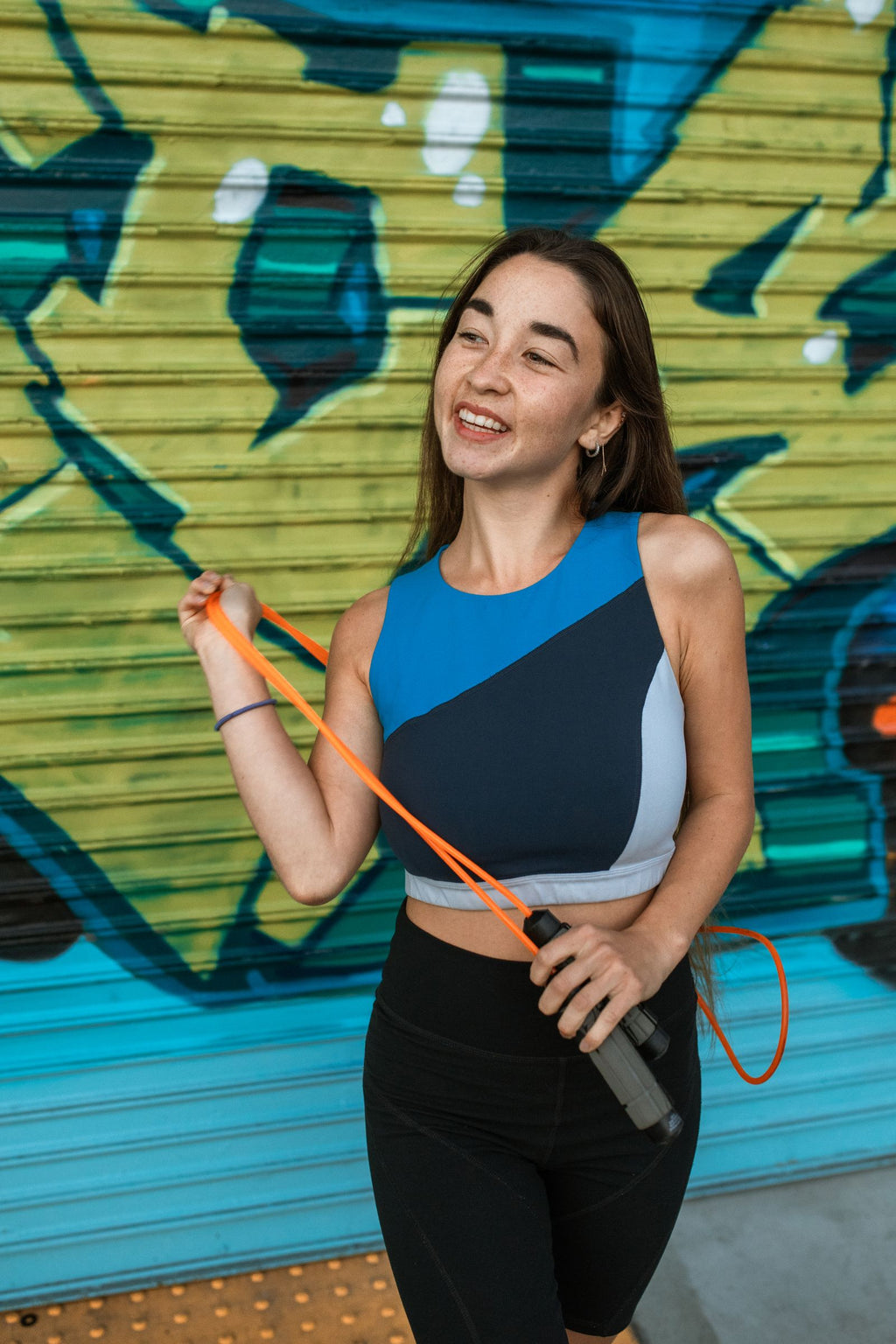 Cheerful woman holding a jump rope in vibrant sportswear