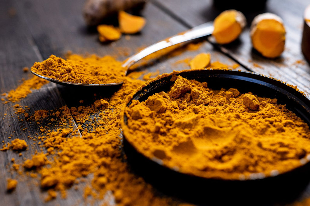 Vibrant turmeric powder and root on a rustic wooden table