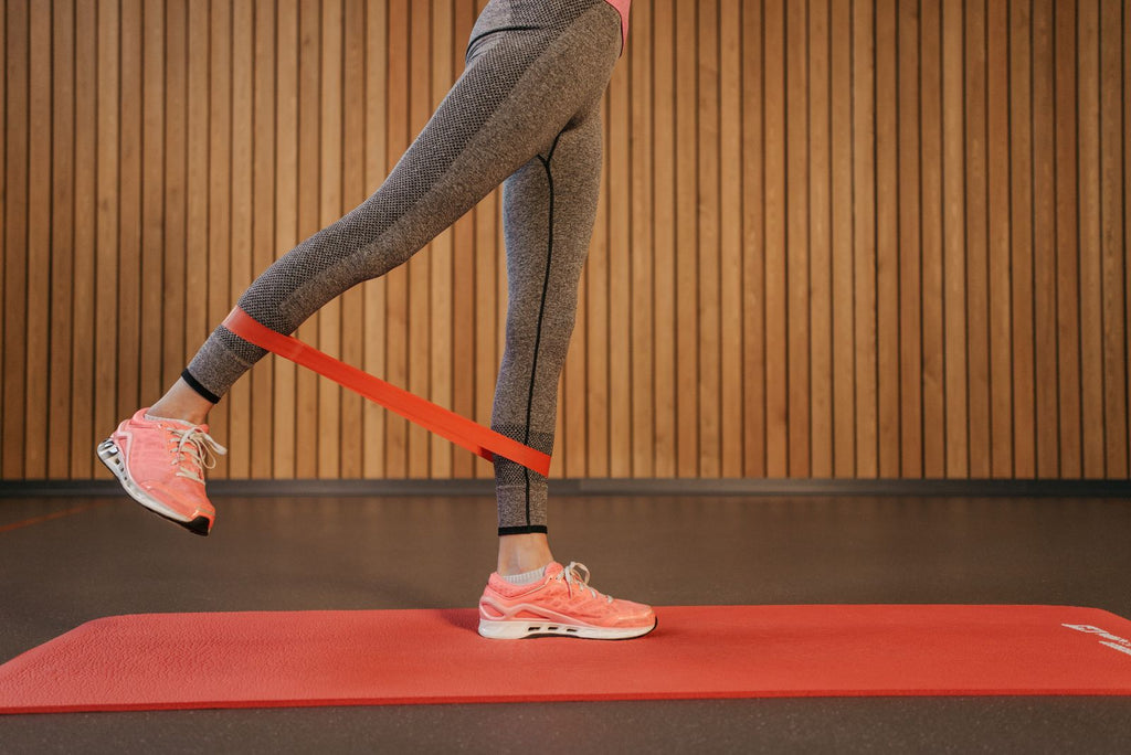 Woman doing leg exercises with a resistance band on a yoga mat