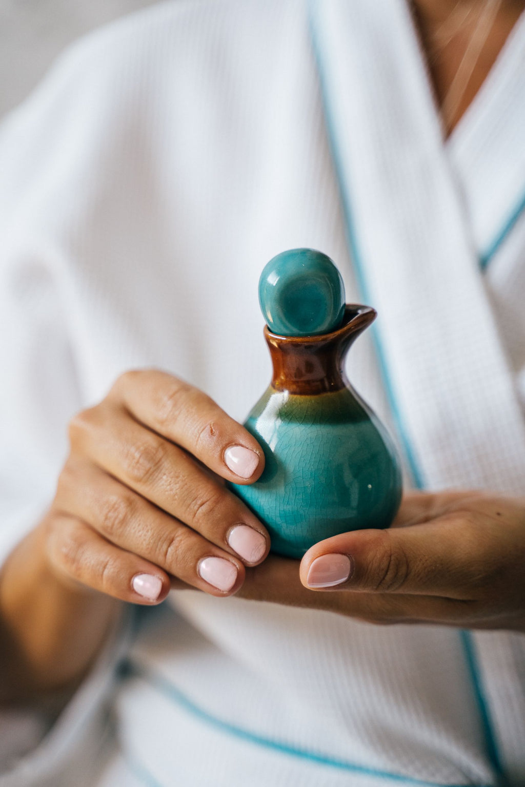Hands holding a ceramic massage oil bottle