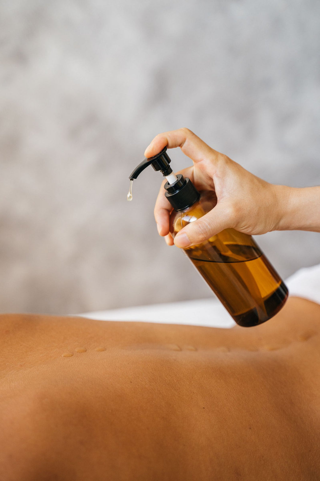 Hand dispensing massage oil from a pump bottle