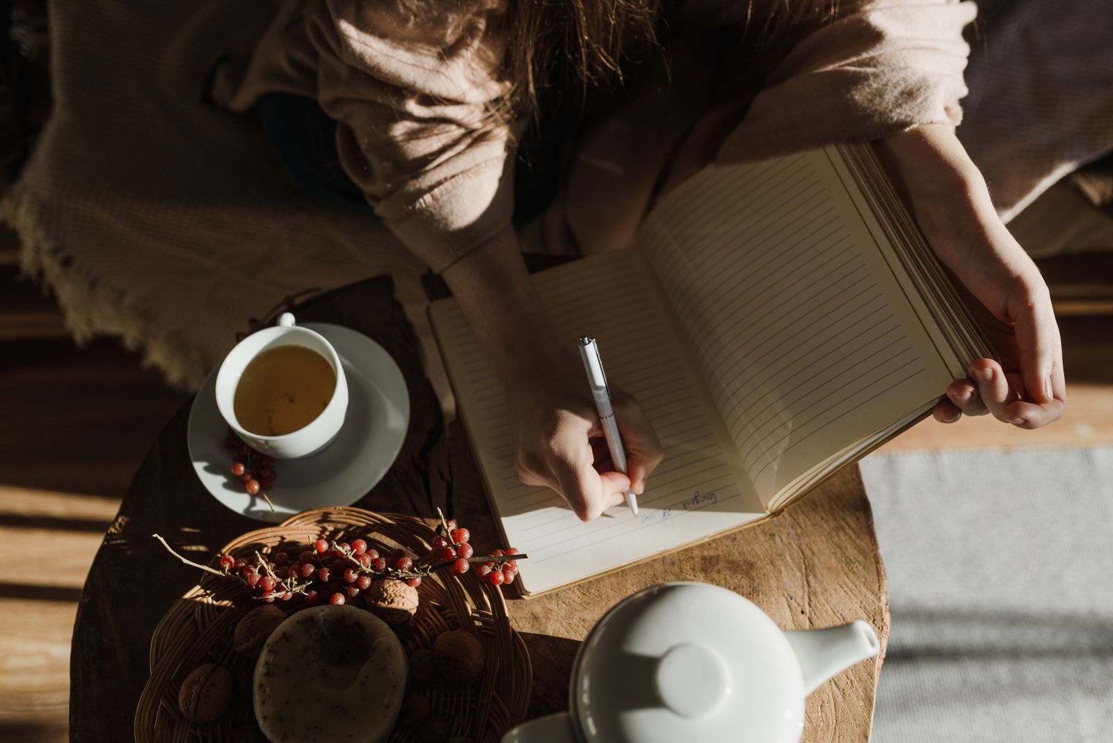 Person journaling in a cozy setting with tea