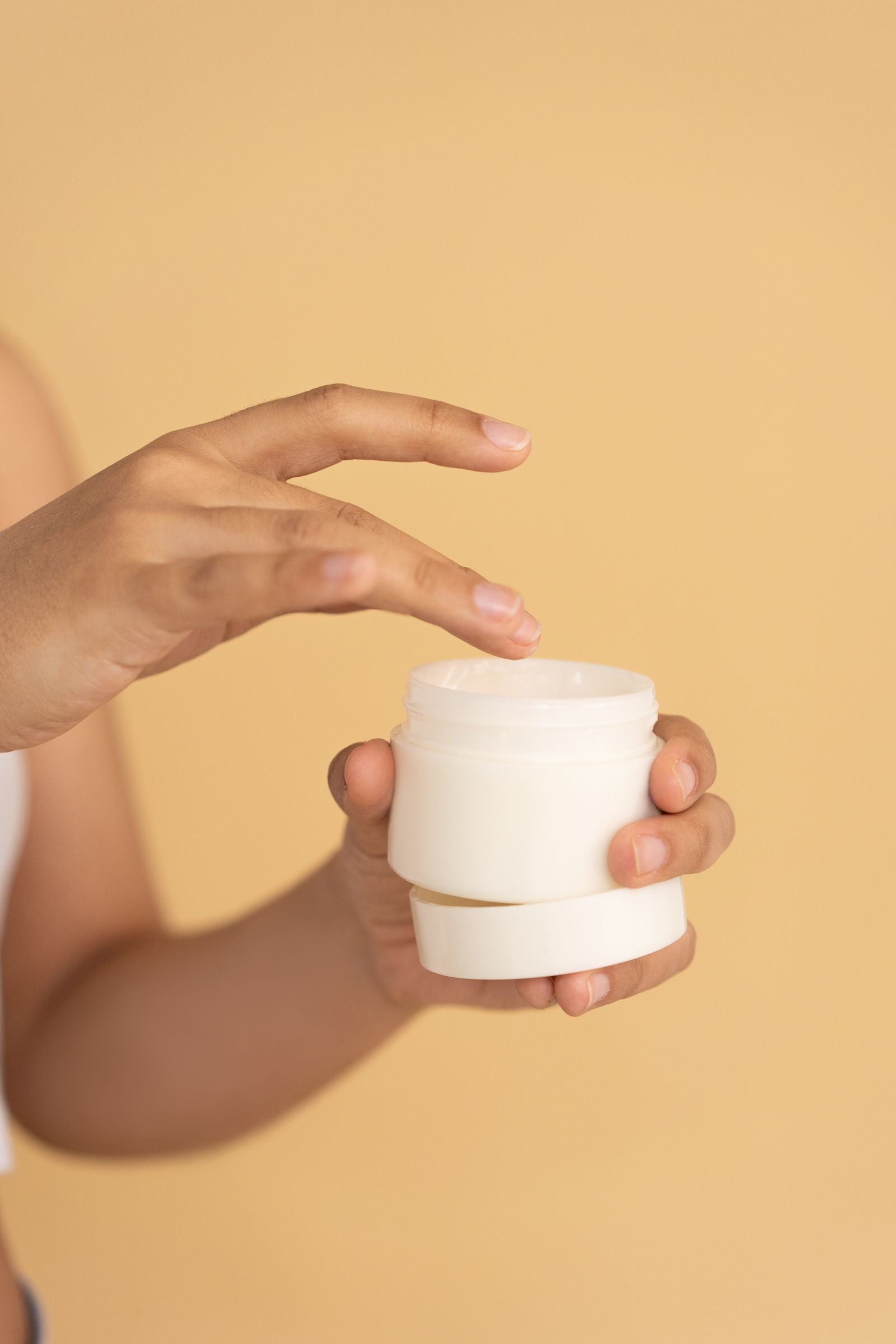 Hand applying face cream from a jar
