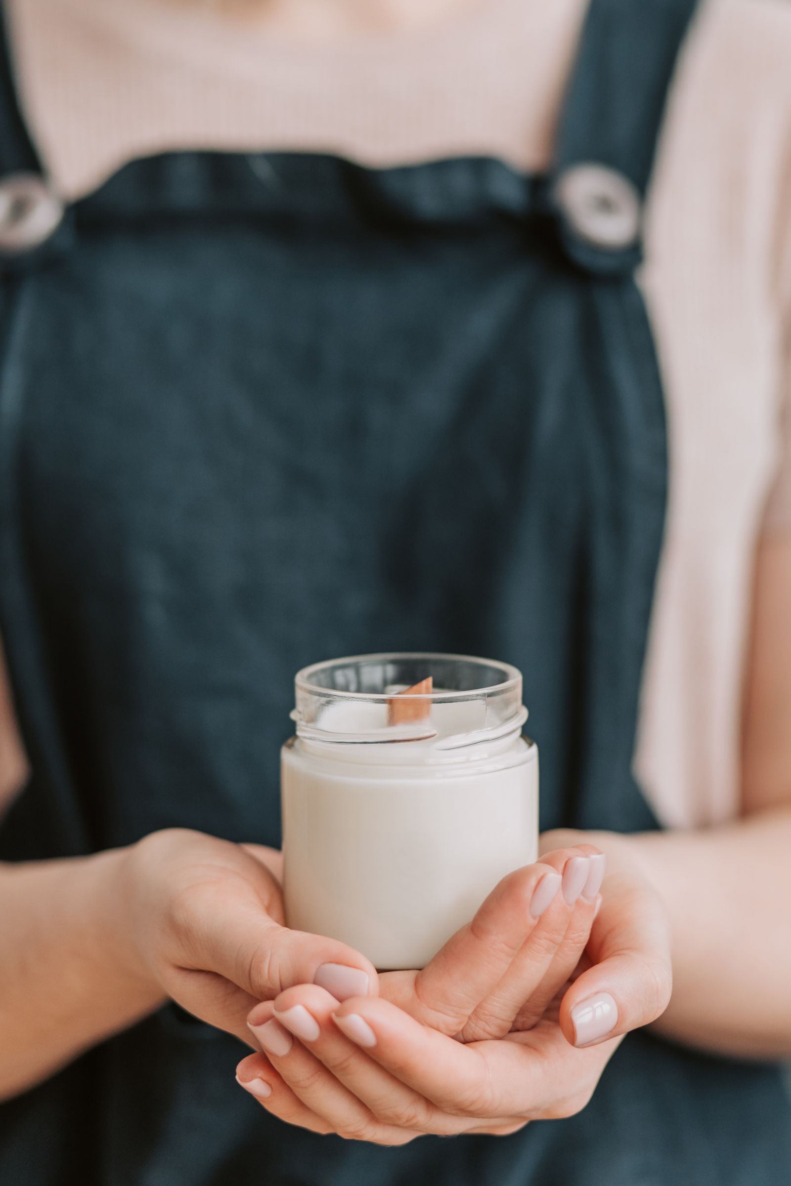Hands holding a handmade candle in a glass jar