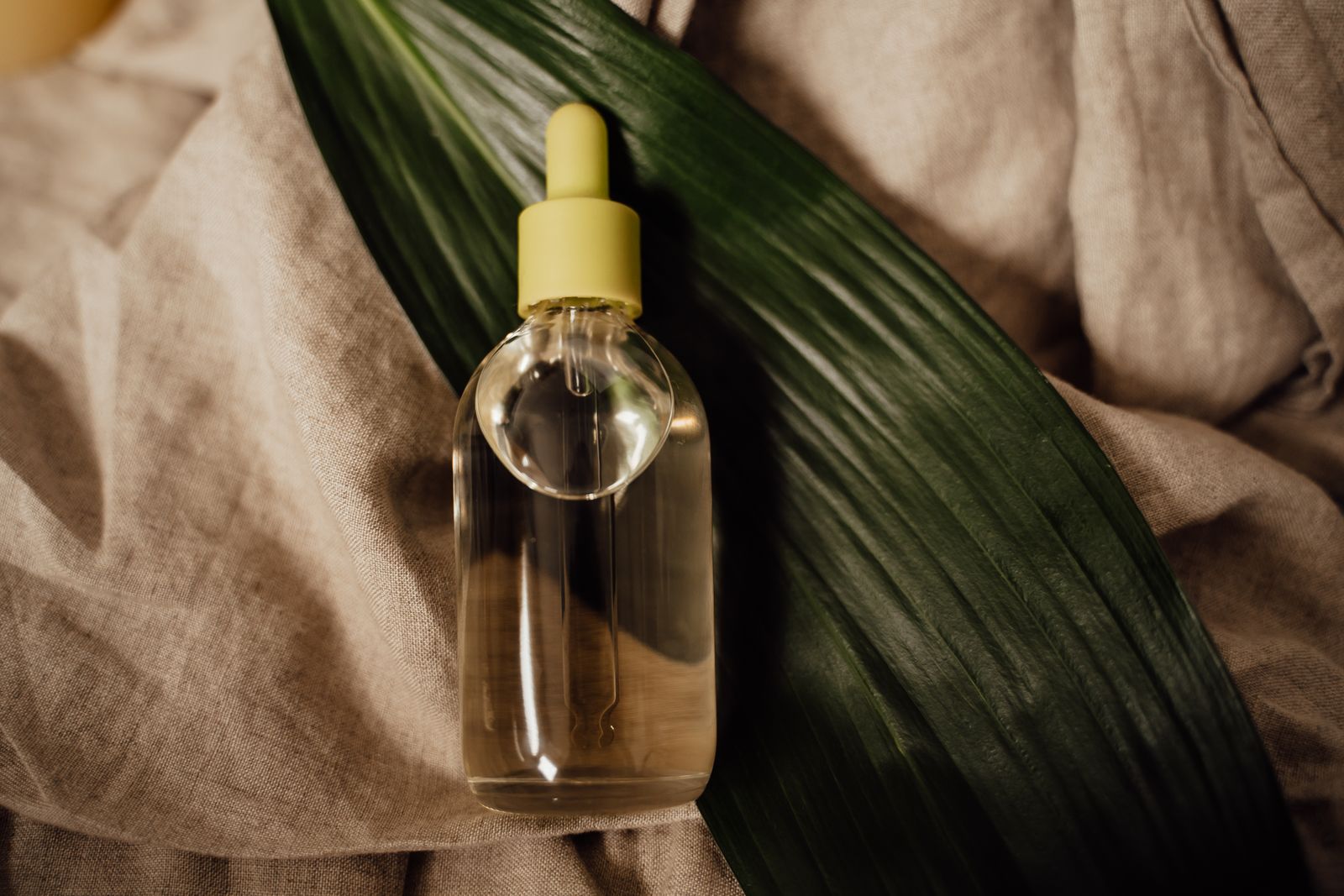 Glass dropper bottle of botanical oil on linen