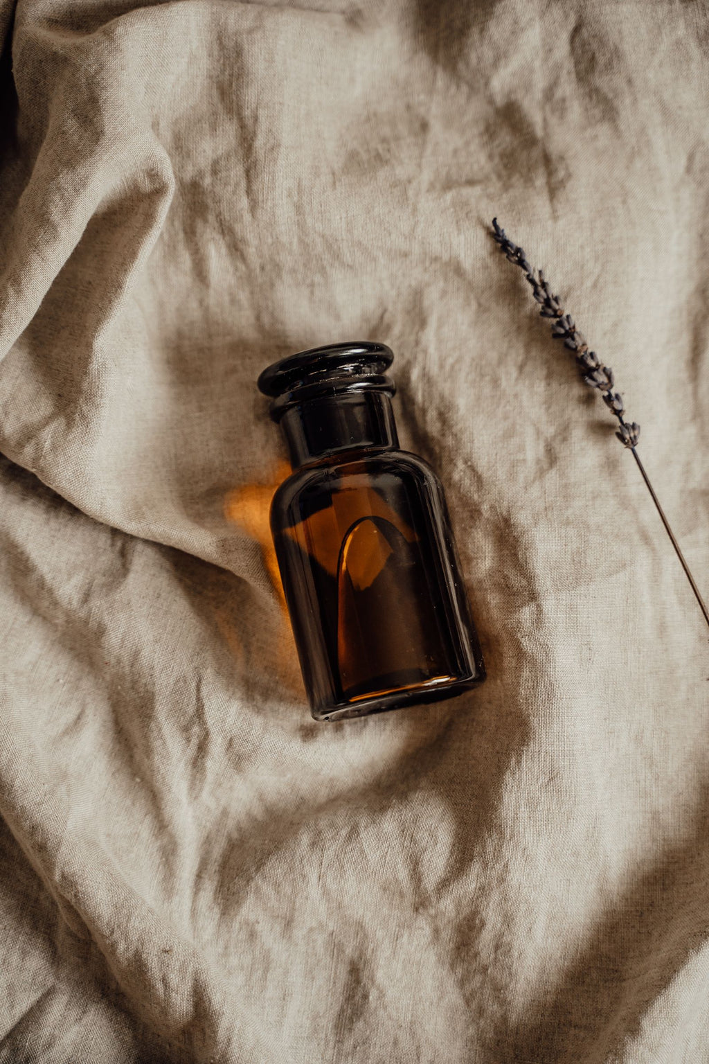 Amber glass bottle with lavender on soft fabric