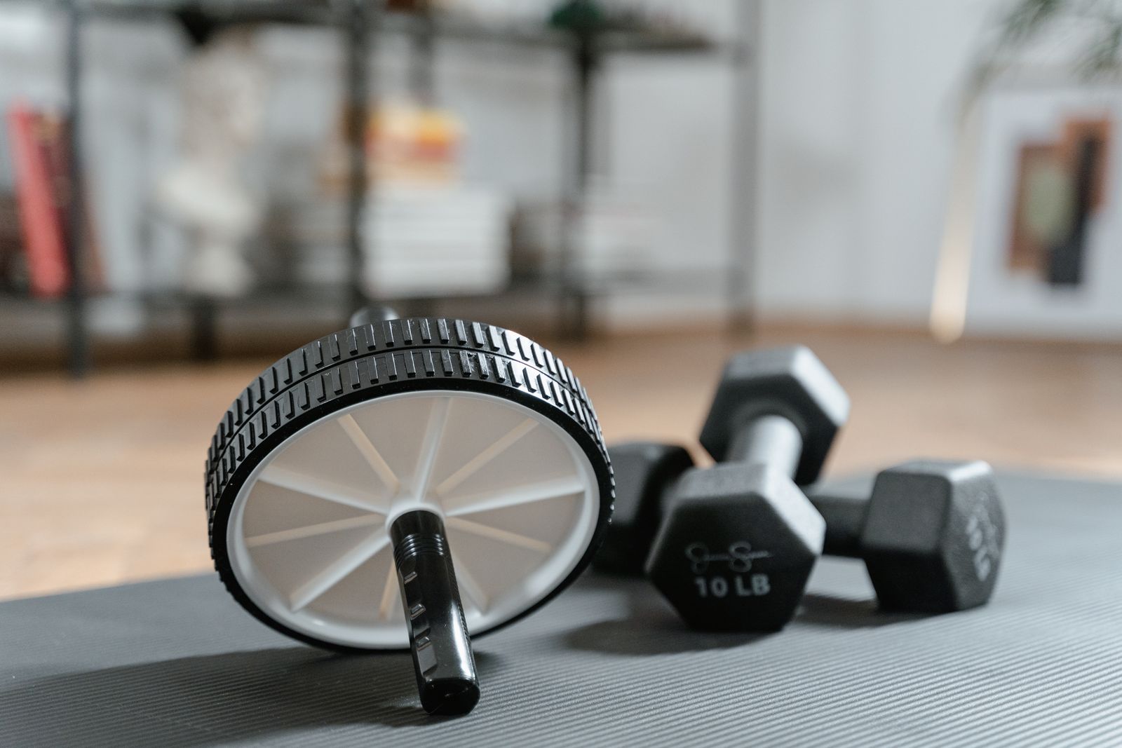 Ab roller and dumbbells laid out on a yoga mat