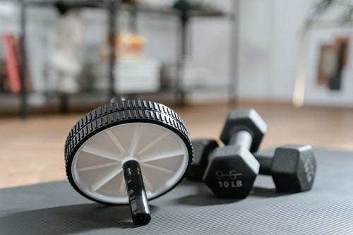 Ab roller and dumbbells laid out on a yoga mat