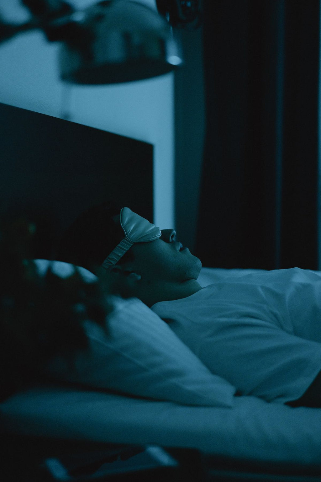Man wearing a sleep mask lying in bed