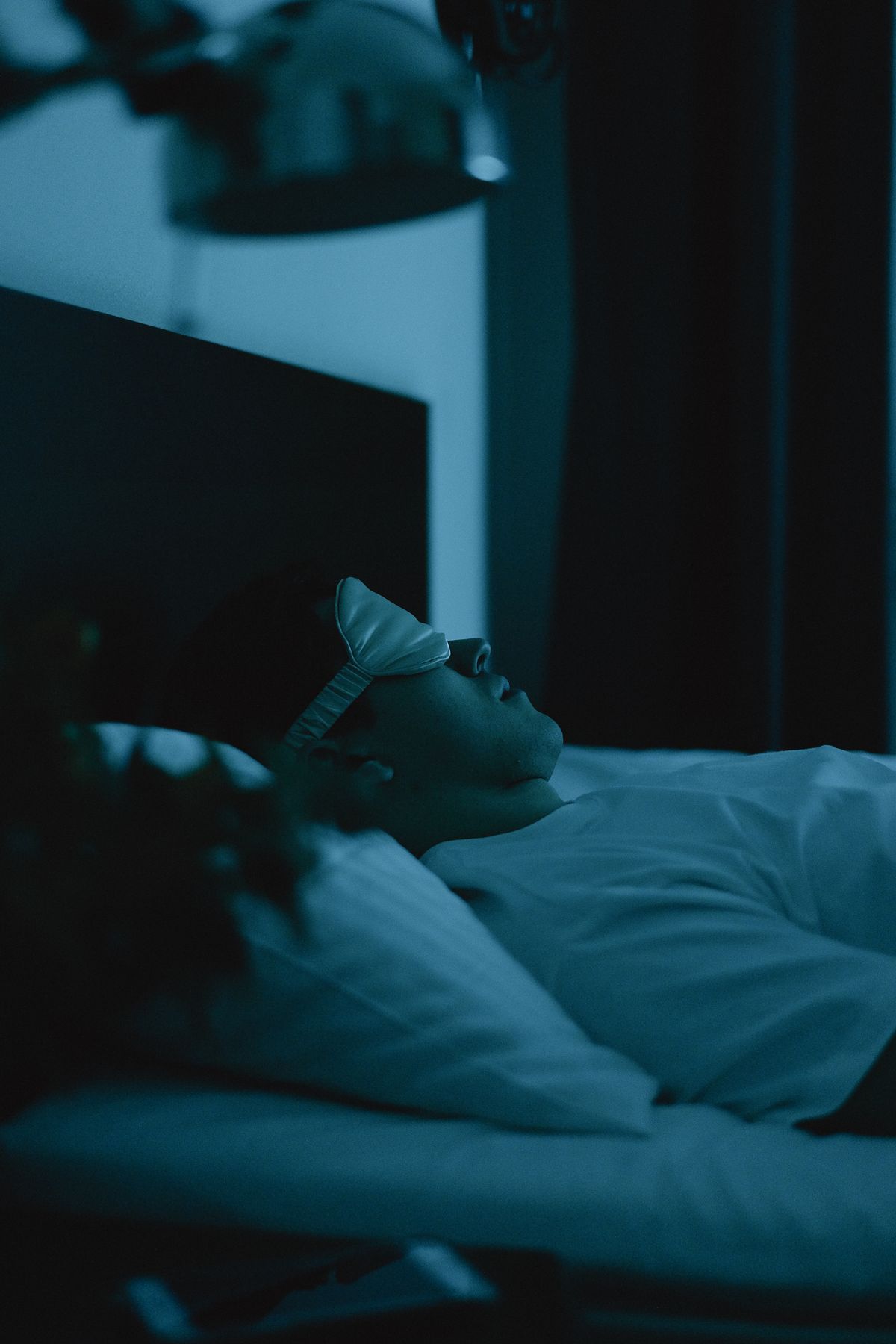 Man wearing a sleep mask lying in bed