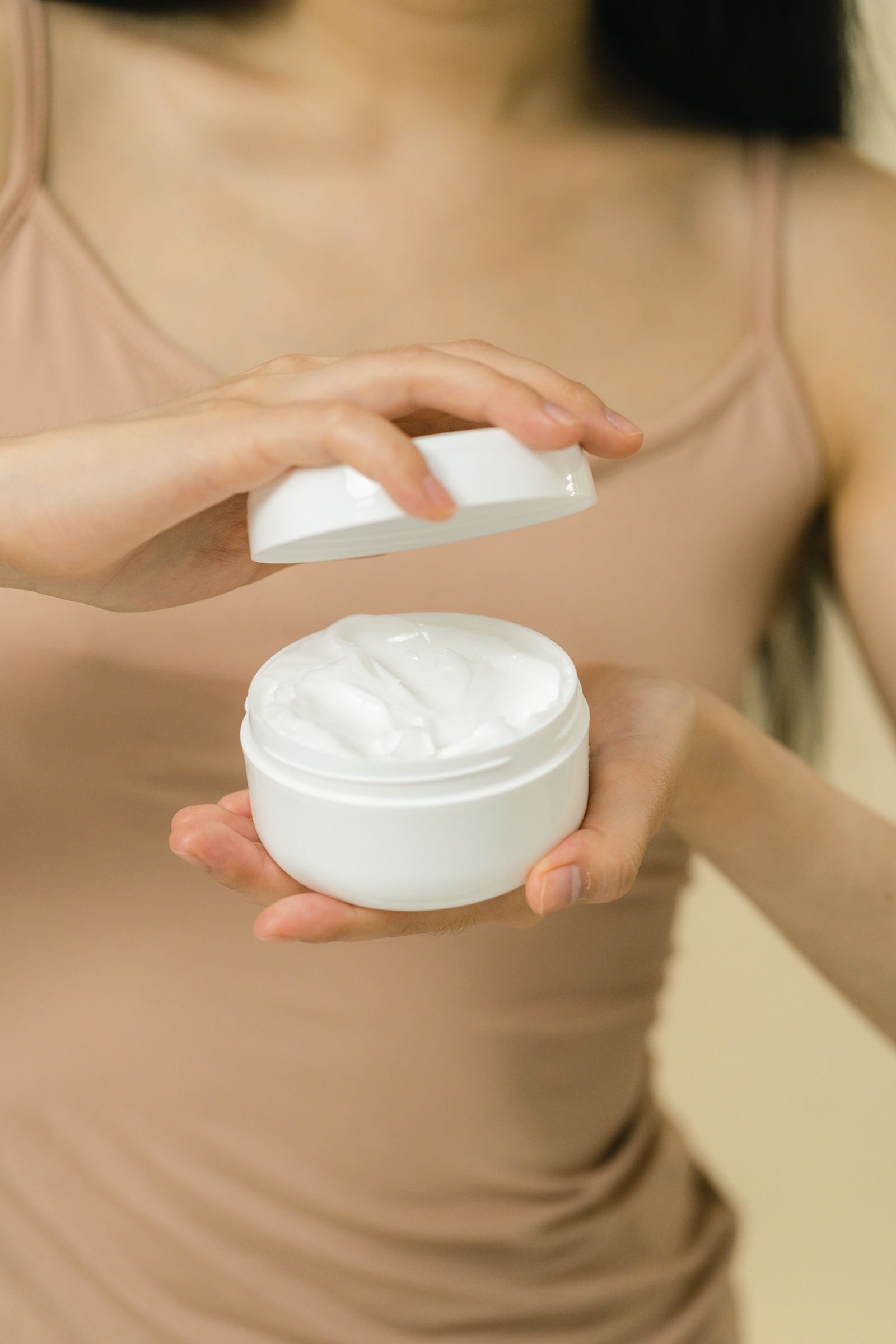 Hands opening a jar of cosmetic cream